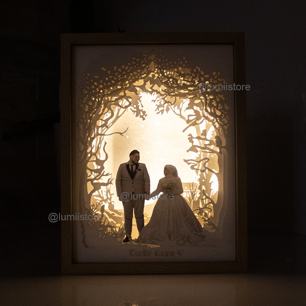 A custom wedding portrait lightbox. The centerpiece showcases a beautiful wedding portrait, while layers of carefully crafted cardstock create a lush and vibrant woodland setting. Ideal for unique wedding decor &personalized gifts.