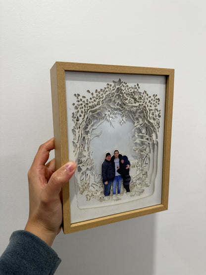 A custom family portrait lightbox. The centerpiece showcases a beautiful family portrait, while layers of carefully crafted cardstock create a lush and vibrant woodland setting. Ideal for unique home decor & personalized gifts.