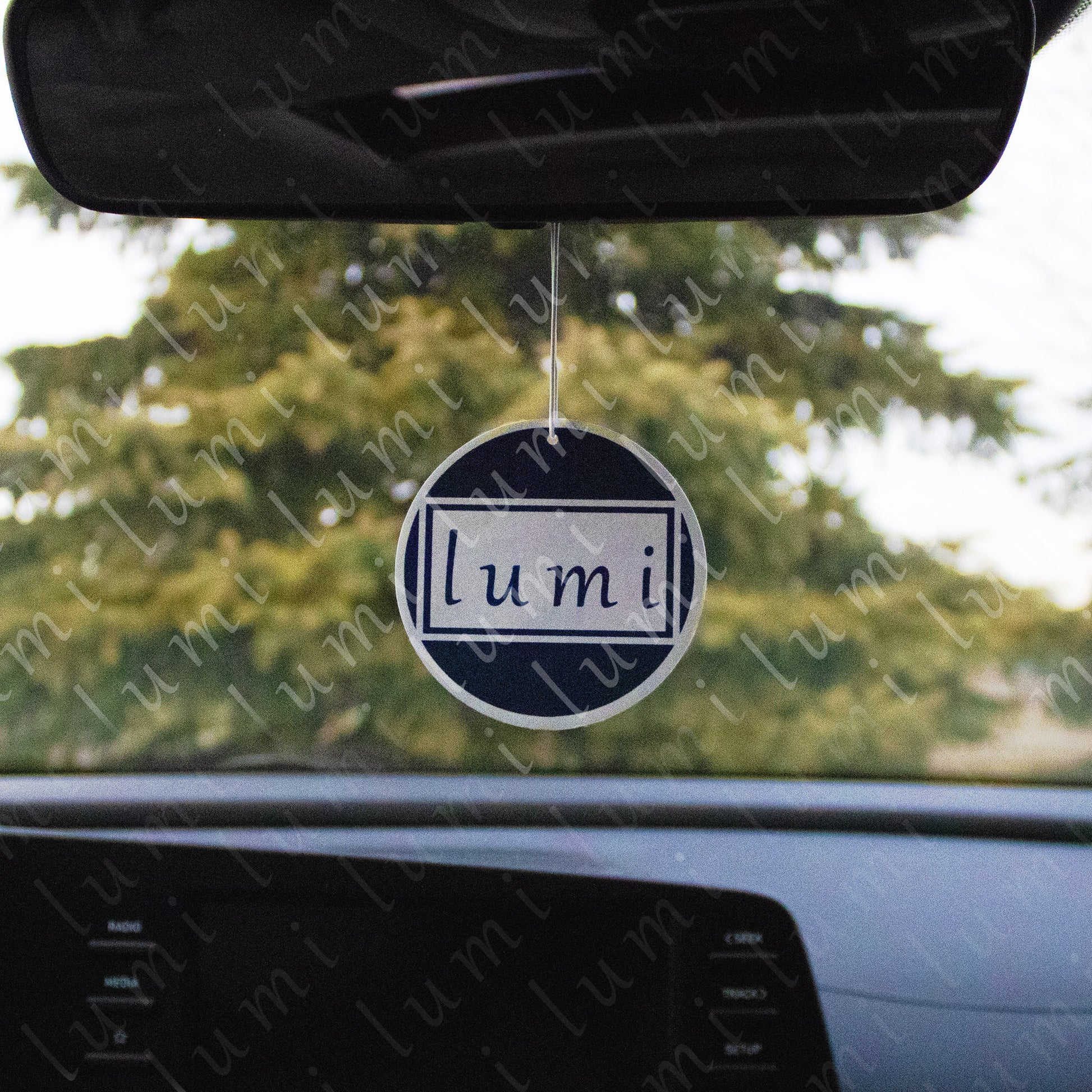 An image of a  air freshener with the LUMi Store logo prominently displayed on it. The logo consists of the letters 'LUMi' in a modern font The air freshener has a circular shape and a white string for hanging.