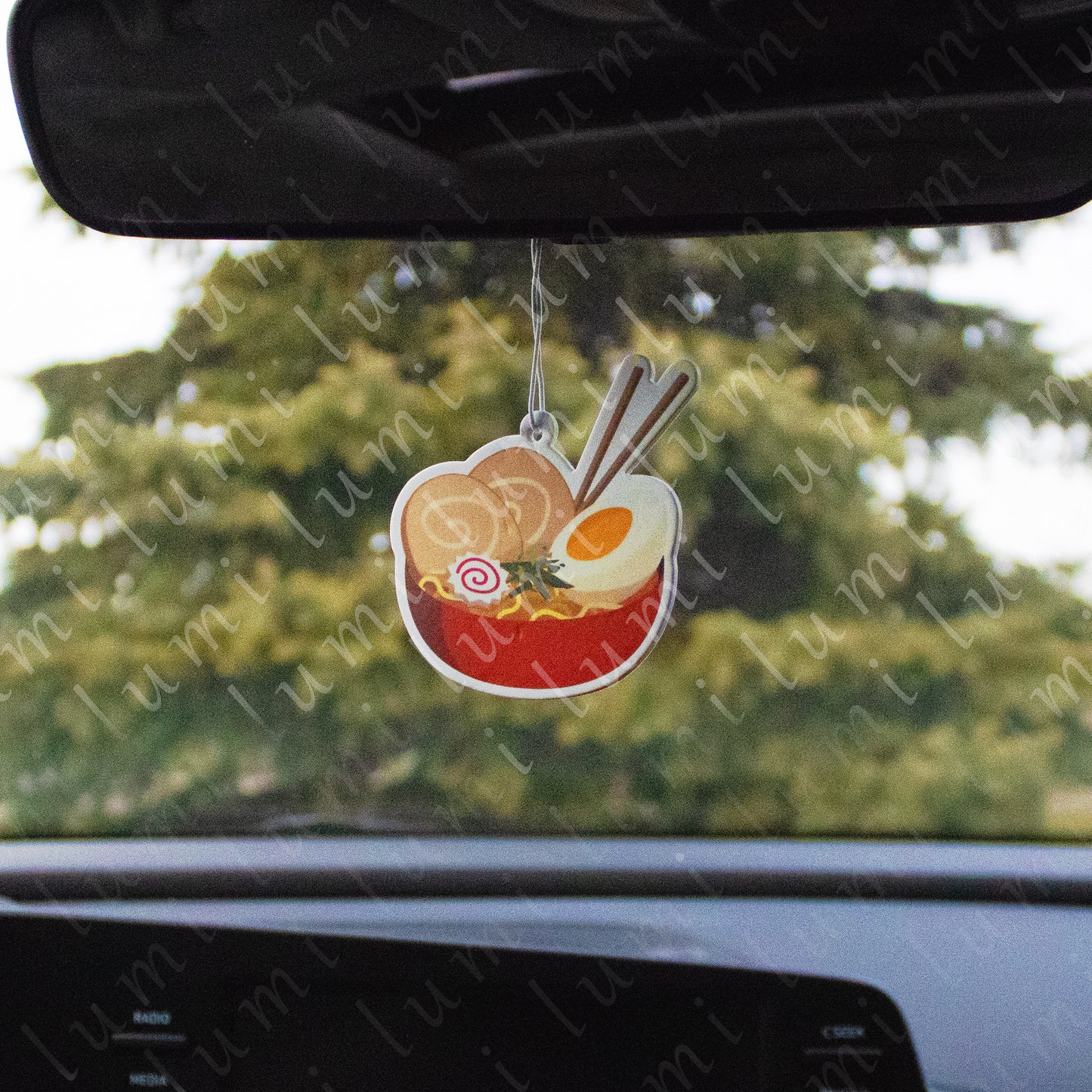 An image of an Ichiraku Ramen air freshener, featuring a bowl of steaming ramen with chopsticks and the Ichiraku Ramen logo in the background.